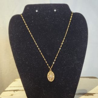Collier avec pendentif en acier inoxydable sur un support noir.